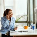 smiling businesswoman adjusting earphones while using smart phon