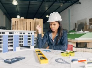 pensive african american woman safety helmet near model building